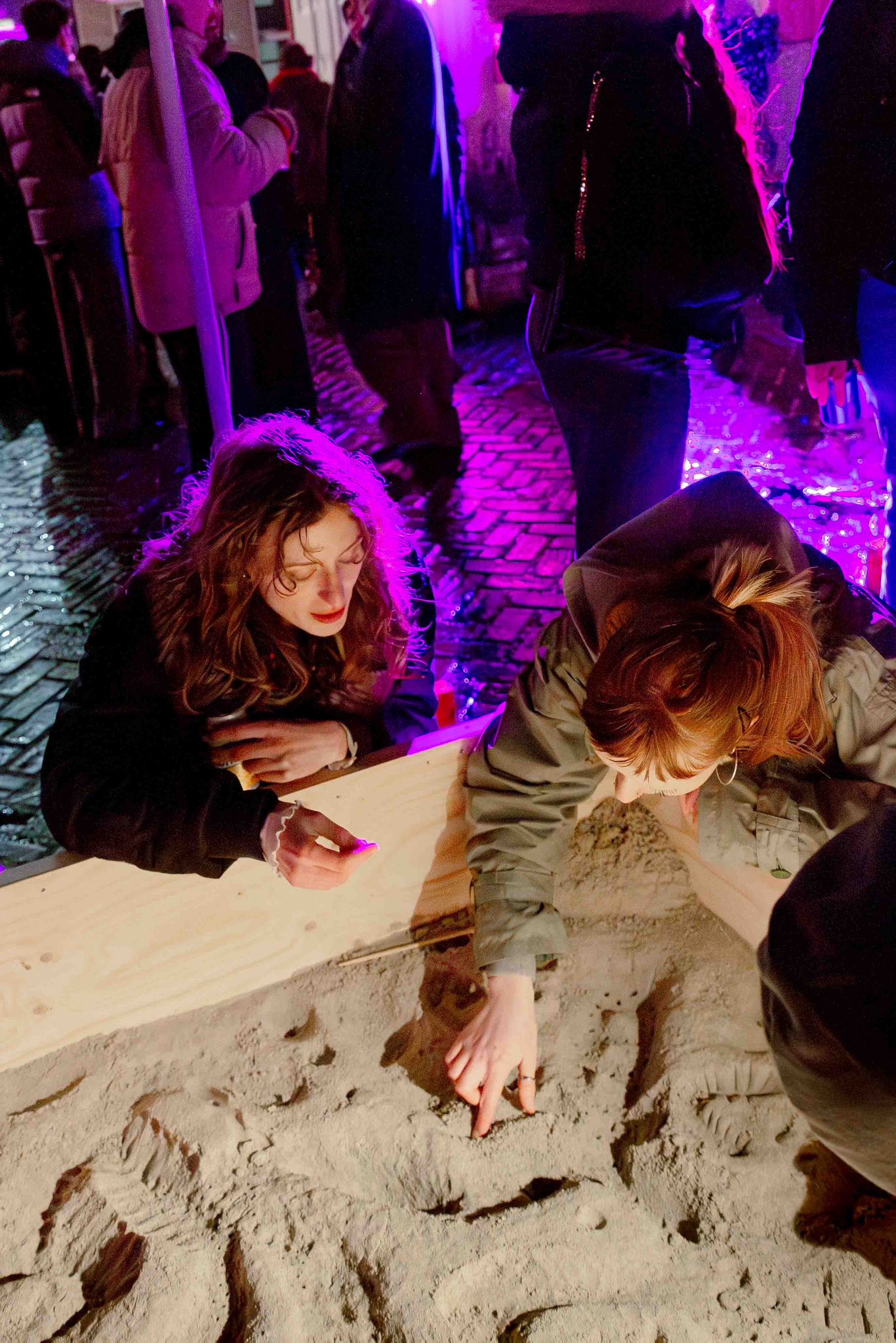 Casting event — participants pressing shapes into sand