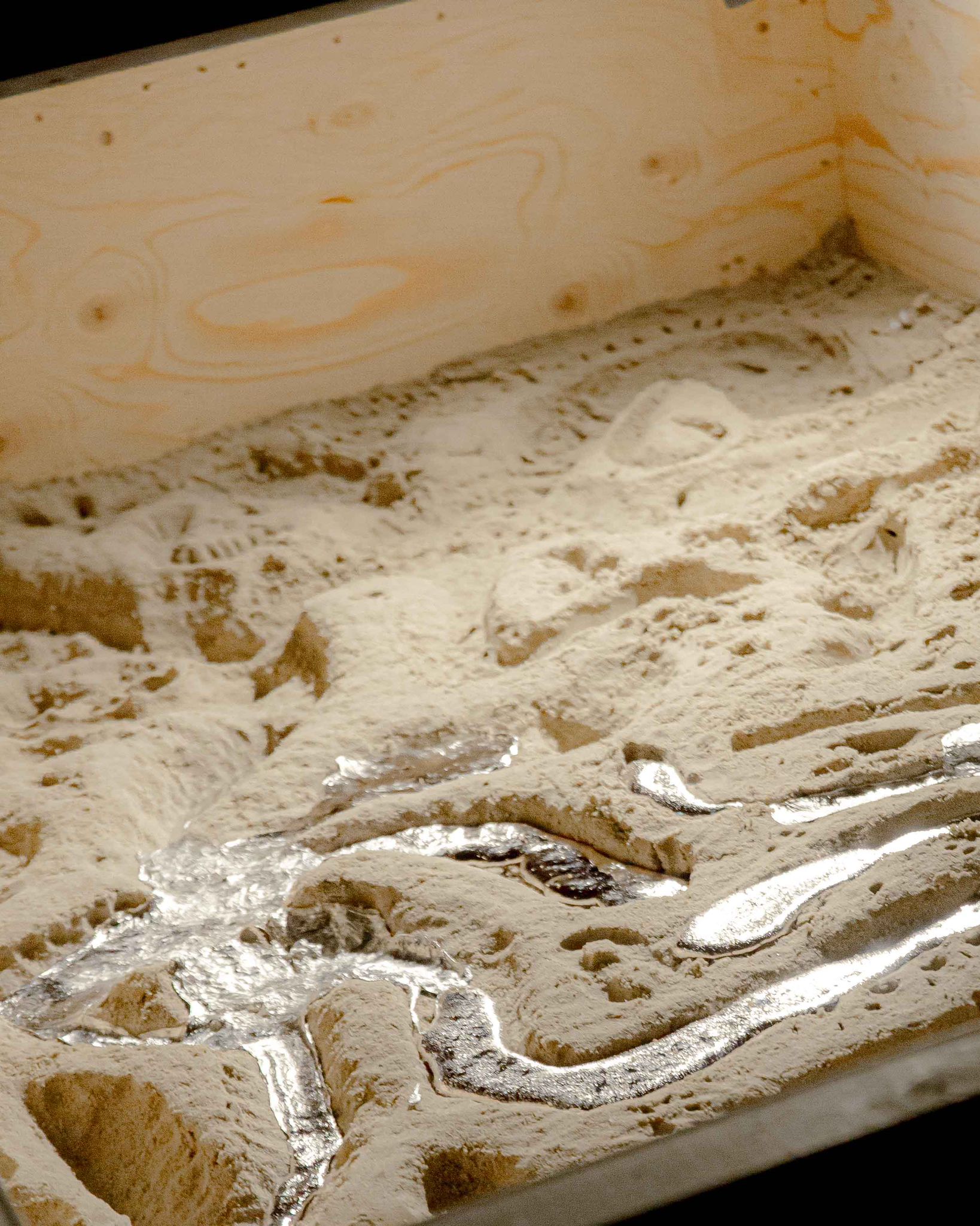 Casting event — freshly cast aluminium cooling in sand